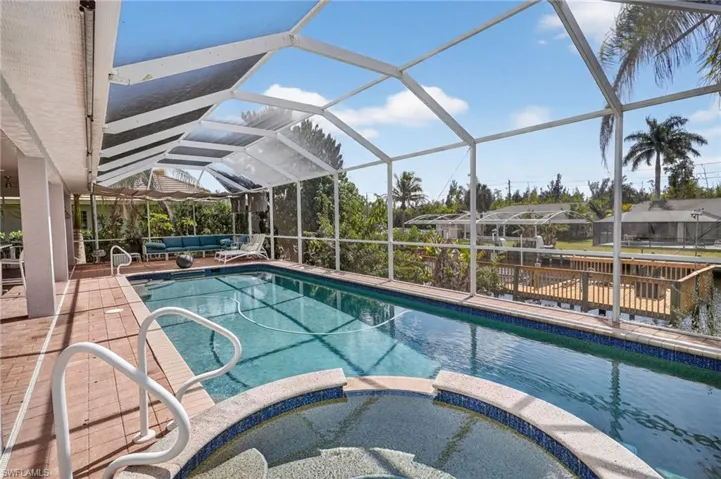 Combined pool / hot tub with a sunroom, outdoor lounge area, a lanai, and a patio area