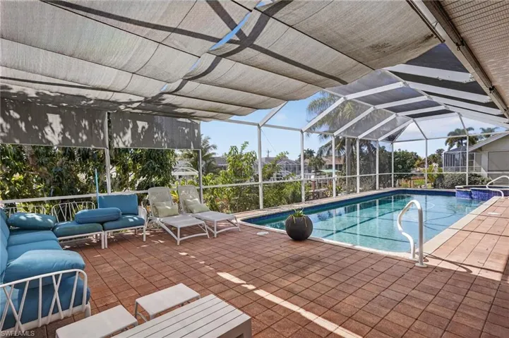 Swimming pool with a sunroom, a patio area, and glass enclosure