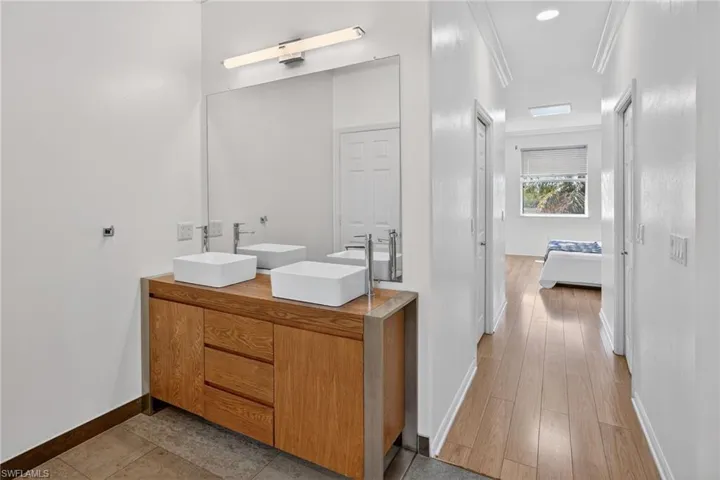 Full bathroom featuring double vanity, ornamental molding, and ensuite bath