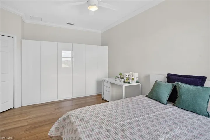 Bedroom with crown molding, dark wood finished floors, and ceiling fan
