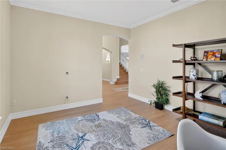Sitting room featuring crown molding, arched walkways, and light wood-style flooring