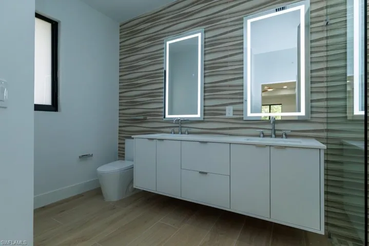 Full bathroom featuring toilet, a sink, double vanity, and wood finished floors