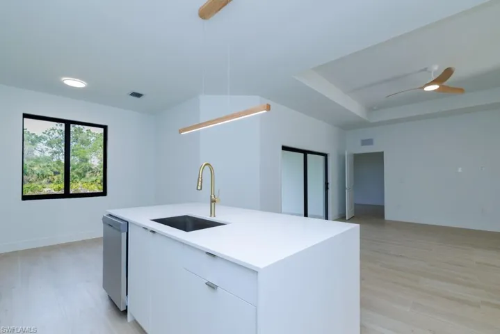 Kitchen featuring a tray ceiling, a sink, dishwasher, visible vents, and ceiling fan