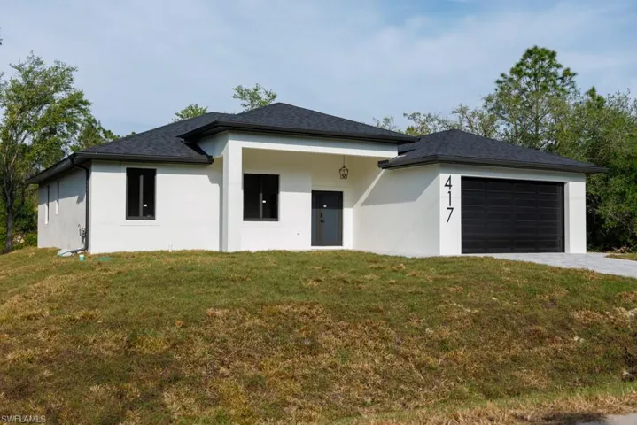 Prairie-style house featuring stucco siding, an attached garage, a front lawn, and driveway
