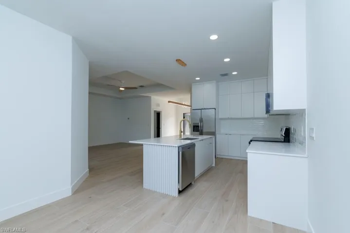 Kitchen featuring light countertops, stainless steel appliances, tasteful backsplash, and light wood finished floors