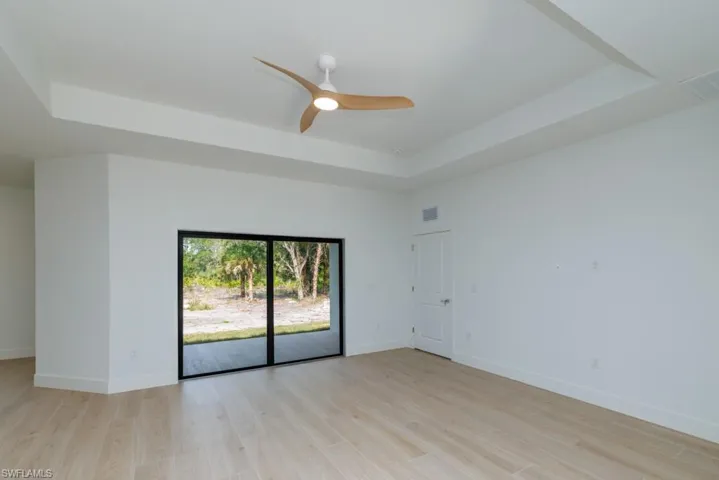 Unfurnished room with visible vents, light wood-style flooring, baseboards, a ceiling fan, and a raised ceiling