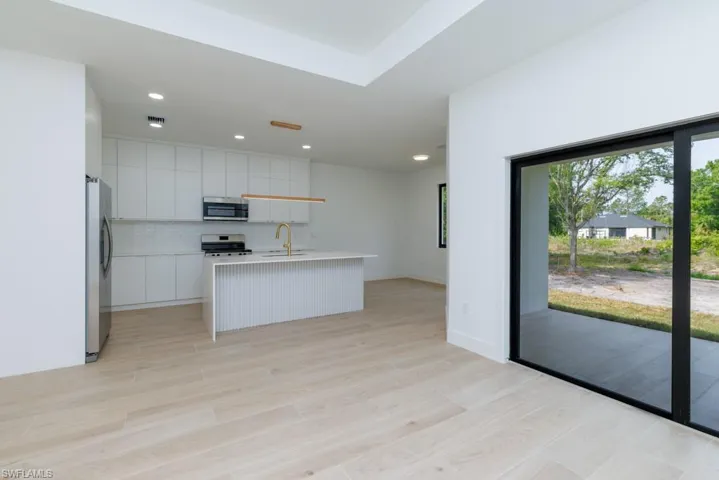 Kitchen featuring an island with sink, light countertops, backsplash, modern cabinets, and stainless steel appliances