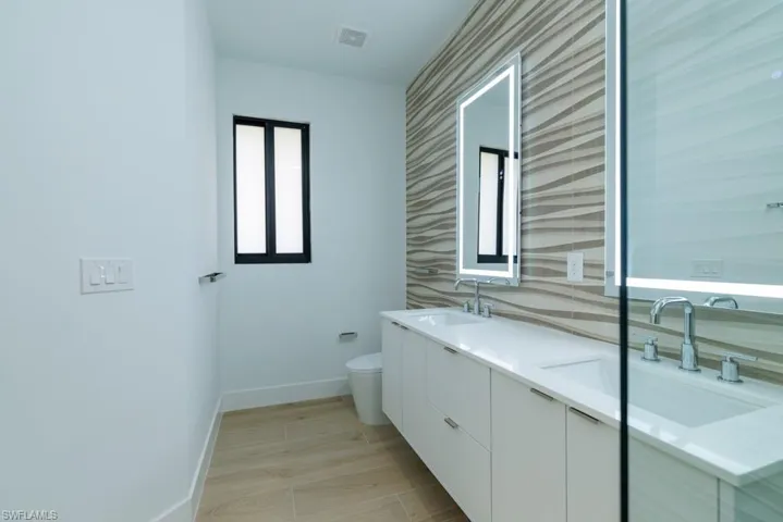 Bathroom with toilet, a sink, baseboards, and visible vents