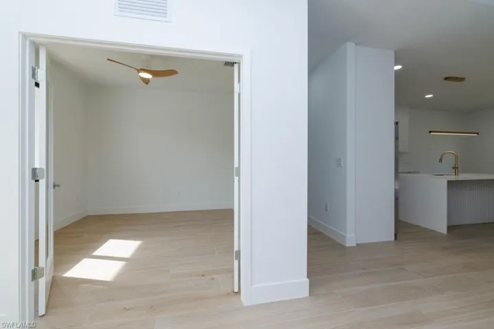 Hall with baseboards, light wood-type flooring, visible vents, and a sink