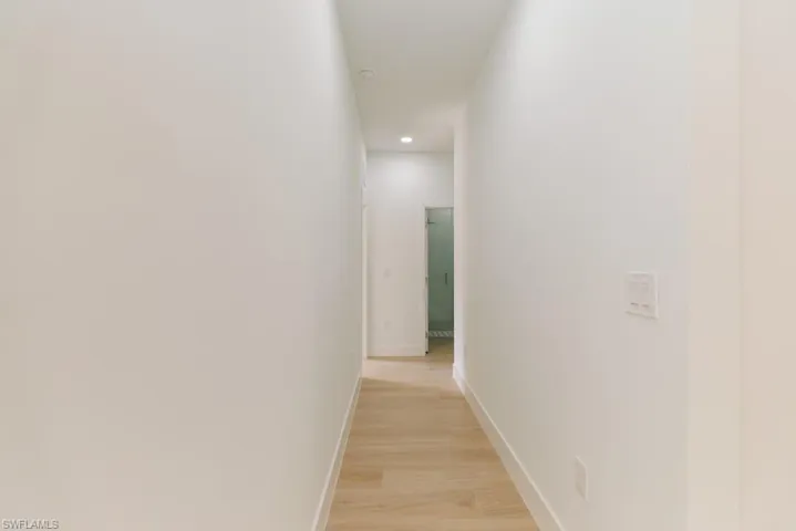 Hall featuring baseboards, light wood finished floors, and recessed lighting