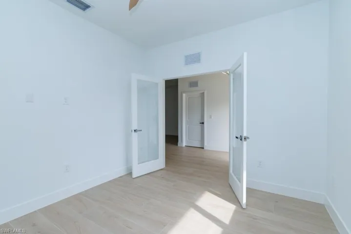 Spare room with light wood finished floors, baseboards, visible vents, and ceiling fan