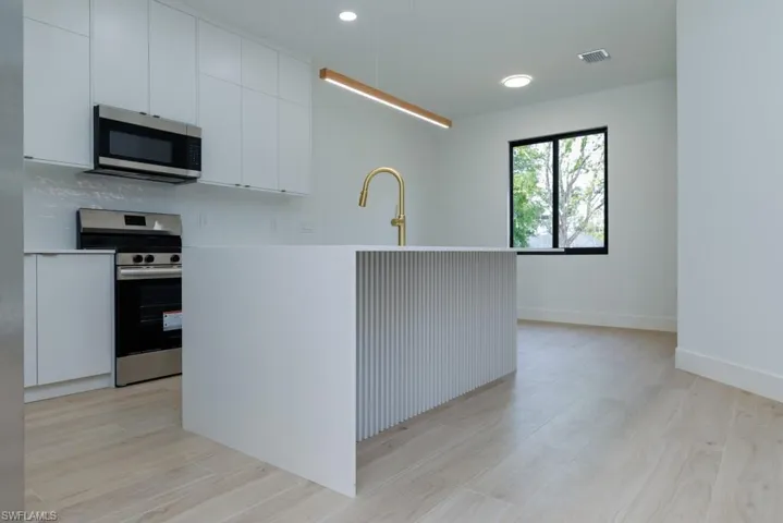 Kitchen with white cabinets, a sink, appliances with stainless steel finishes, and light wood-style floors