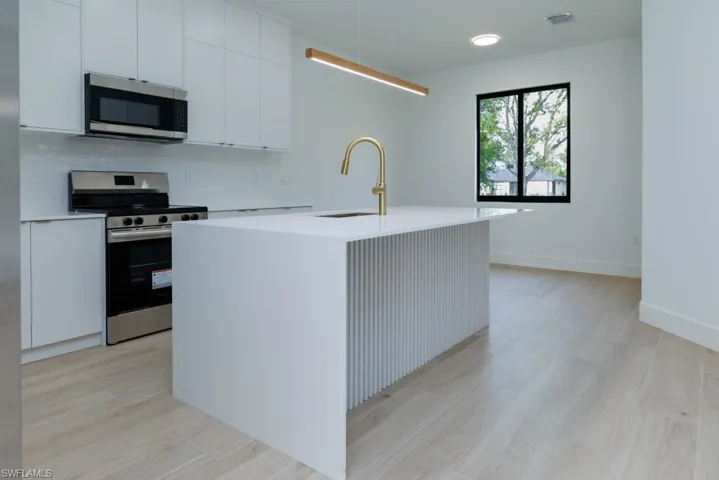 Kitchen featuring light countertops, stainless steel appliances, a sink, light wood finished floors, and visible vents