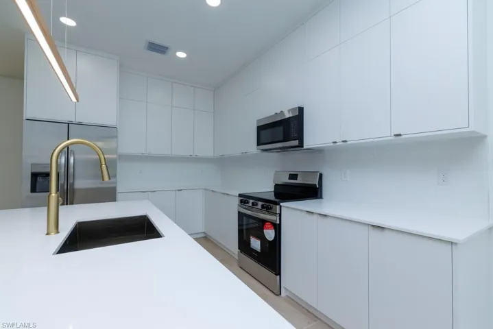 Kitchen with light countertops, visible vents, stainless steel appliances, white cabinetry, and a sink