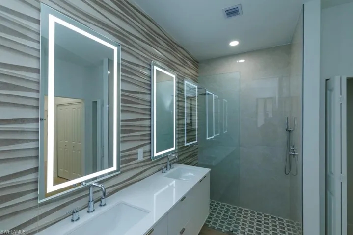 Full bath featuring double vanity, a sink, visible vents, and a walk in shower