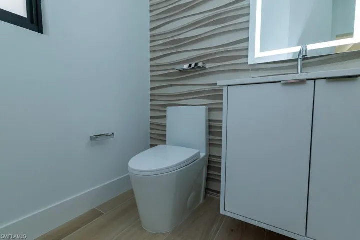 Half bathroom featuring toilet, baseboards, and wood finished floors
