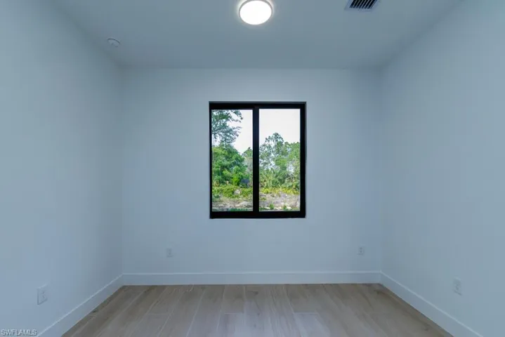 Empty room with baseboards, visible vents, and light wood-style flooring