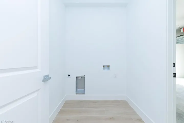Clothes washing area with light wood-type flooring, hookup for an electric dryer, laundry area, baseboards, and hookup for a washing machine