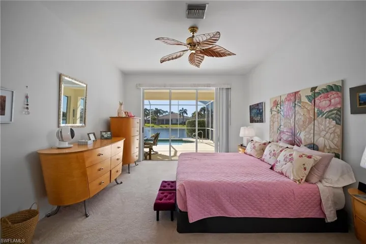 Carpeted bedroom with a water view, ceiling fan, and access to exterior
