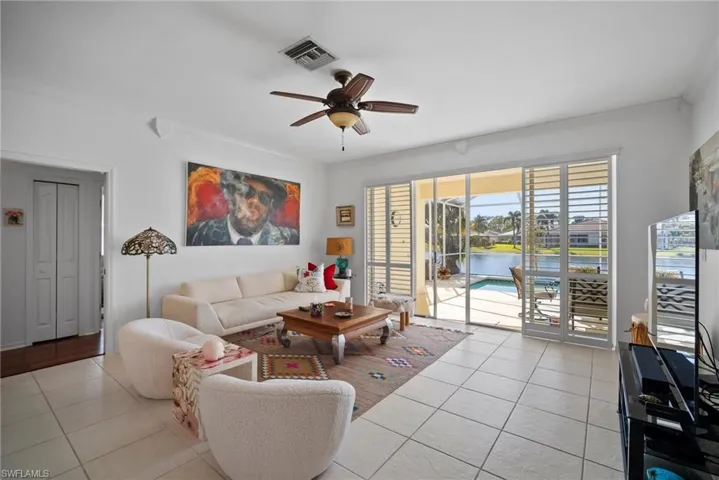 Tiled living room featuring ceiling fan and ornamental molding