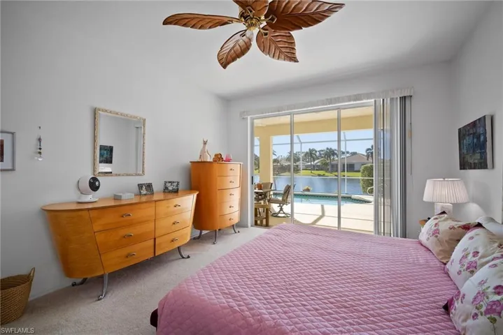 Carpeted bedroom featuring access to outside, ceiling fan, and a water view
