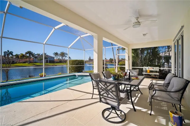 View of swimming pool featuring a lanai, ceiling fan, a patio, a water view, and an outdoor living space