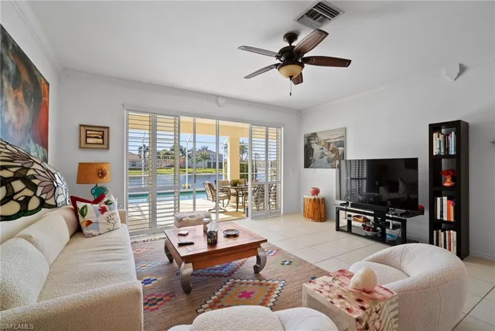 Tiled living room with ornamental molding and ceiling fan