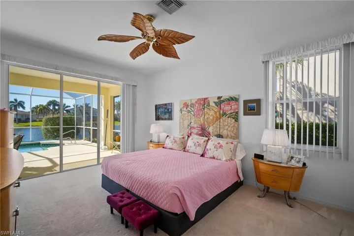 Bedroom featuring multiple windows, a water view, light colored carpet, and access to exterior