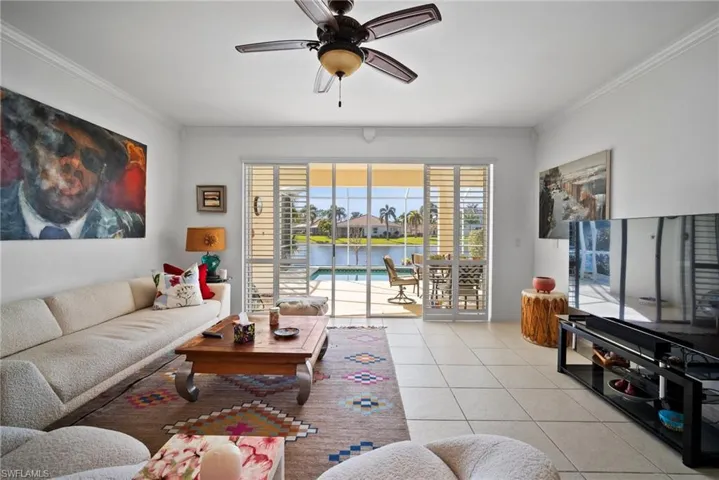 Tiled living room with ornamental molding and ceiling fan
