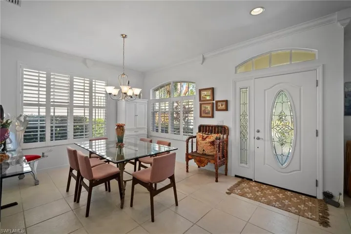 Tiled dining space featuring crown molding and a chandelier