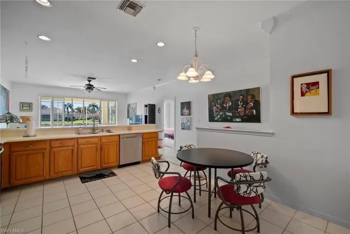 Kitchen with ceiling fan with notable chandelier, sink, hanging light fixtures, stainless steel dishwasher, and light tile patterned floors