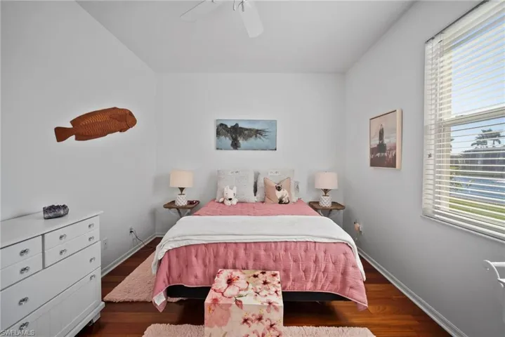 Bedroom with dark wood-type flooring, ceiling fan, and multiple windows