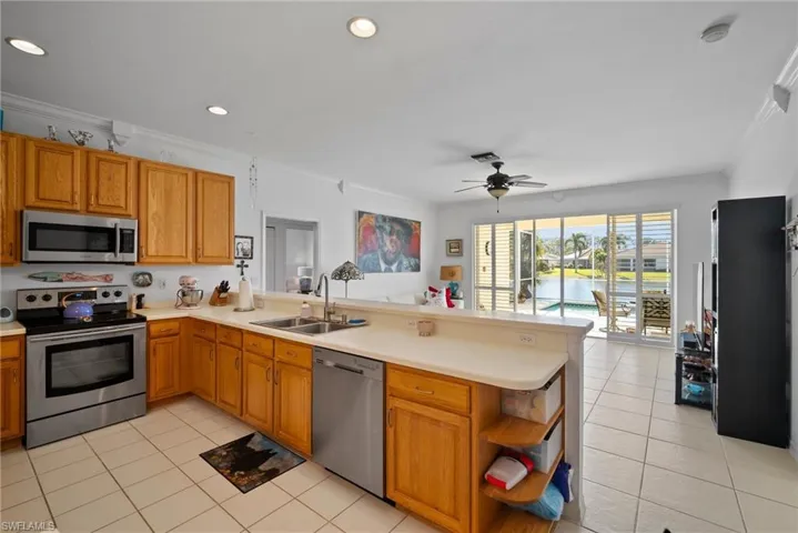 Kitchen with ornamental molding, appliances with stainless steel finishes, sink, and kitchen peninsula