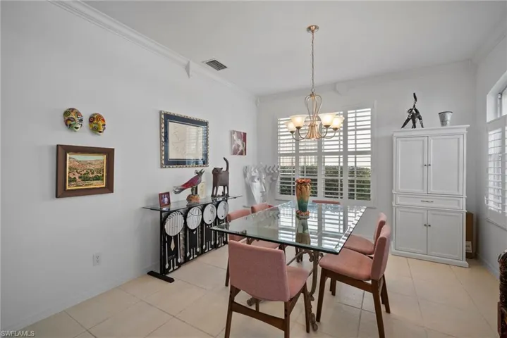 Tiled dining area with crown molding and a chandelier