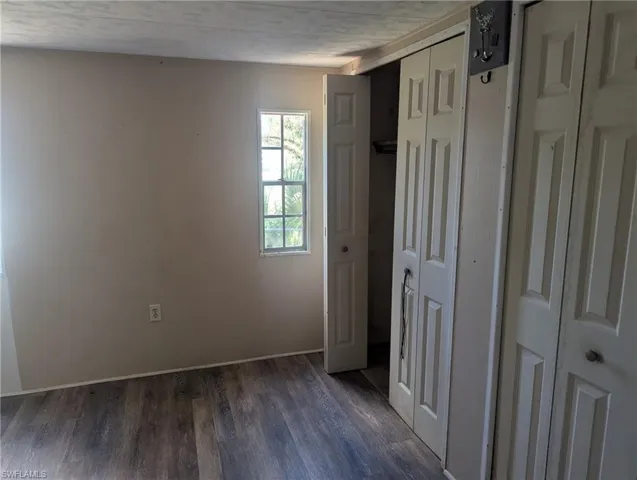 Unfurnished bedroom with baseboards and dark wood finished floors
