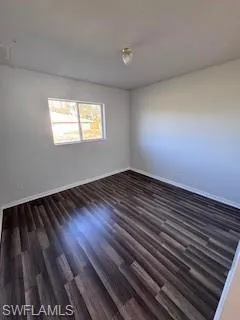 Spare room with dark wood-type flooring