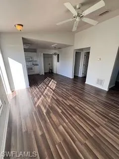 Unfurnished living room featuring lofted ceiling, ceiling fan, and dark hardwood / wood-style floors