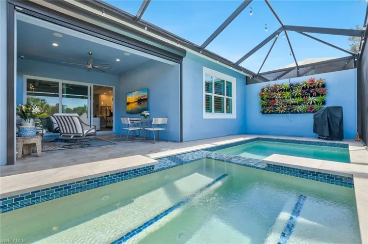 Combined pool / hot tub featuring a sunroom, a patio, area for grilling, a lanai, and outdoor dining space