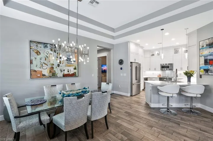 Dining room with wood-style tile floors, a tray ceiling, and a chandelier