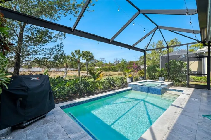 Integrated pool / hot tub featuring a lanai enclosure, a patio area, grilling area, and a sunroom