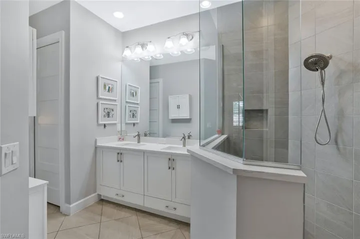 Full bath featuring double vanity, walk in shower, and light tile patterned floors