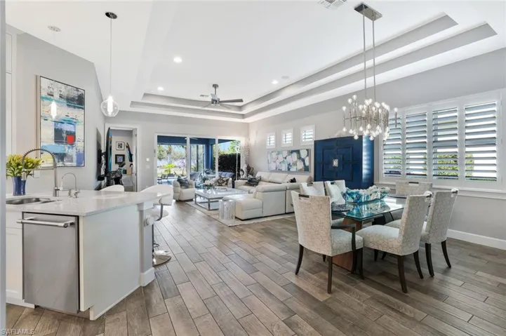 Dining area featuring ceiling fan, hanging lights, light wood-style floors, and a raised ceiling