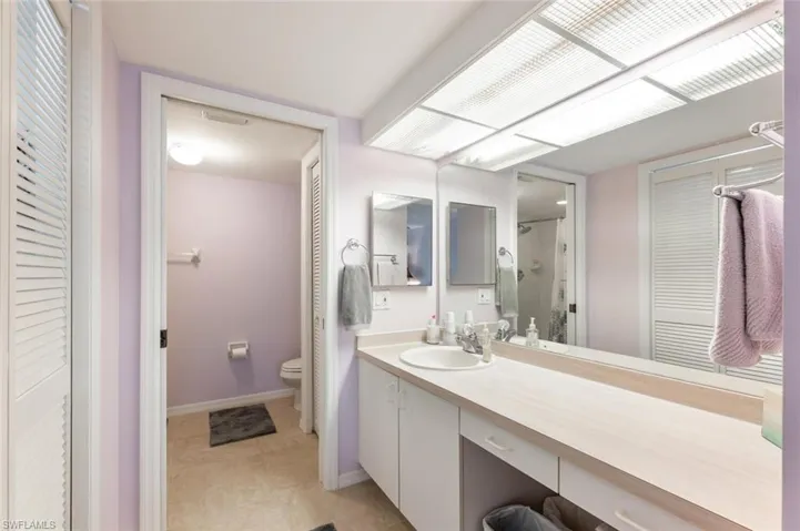 Bathroom with tiled shower, tile patterned floors, vanity, and toilet