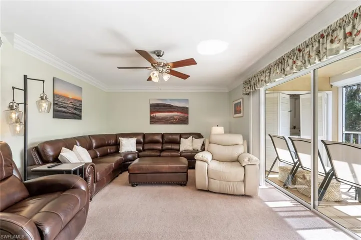 Carpeted living room with ceiling fan and ornamental molding