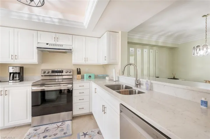 Kitchen featuring appliances with stainless steel finishes, ornamental molding, sink, pendant lighting, and white cabinetry