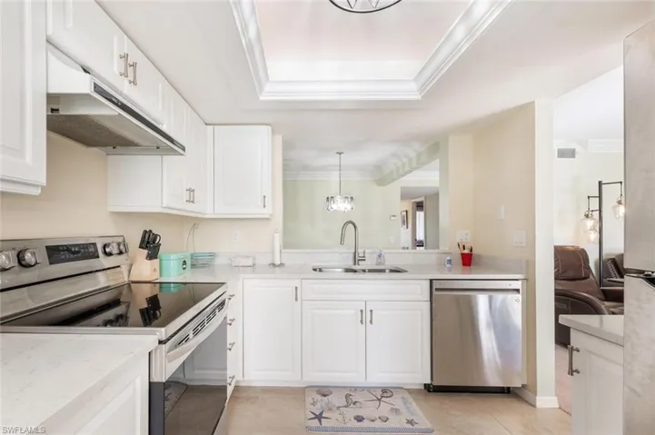 Kitchen featuring sink, white cabinets, decorative light fixtures, and appliances with stainless steel finishes