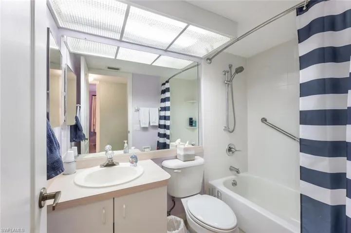 Full bathroom with vanity, shower / bath combination with curtain, and toilet