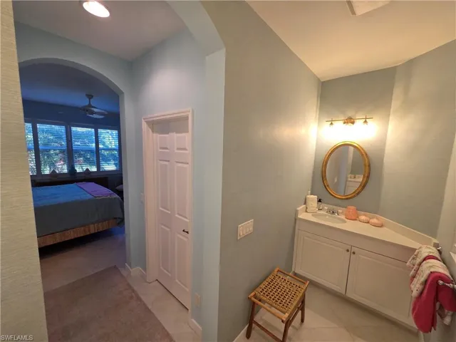Ensuite bathroom featuring vanity, light tile patterned floors, and ceiling fan