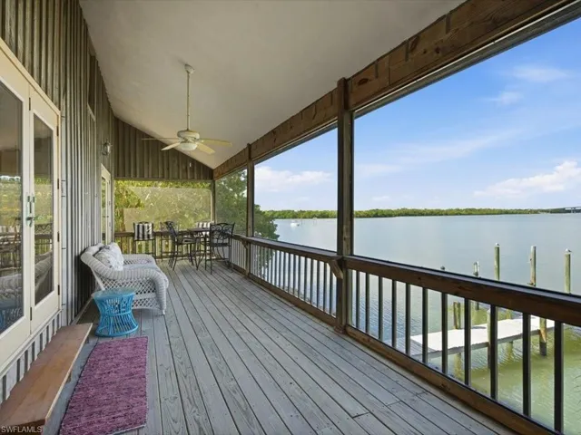 Wooden terrace featuring a water view, outdoor dining area, and ceiling fan