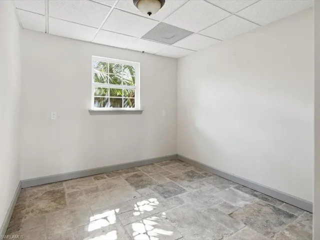 Spare room with a drop ceiling and light stone finish floors